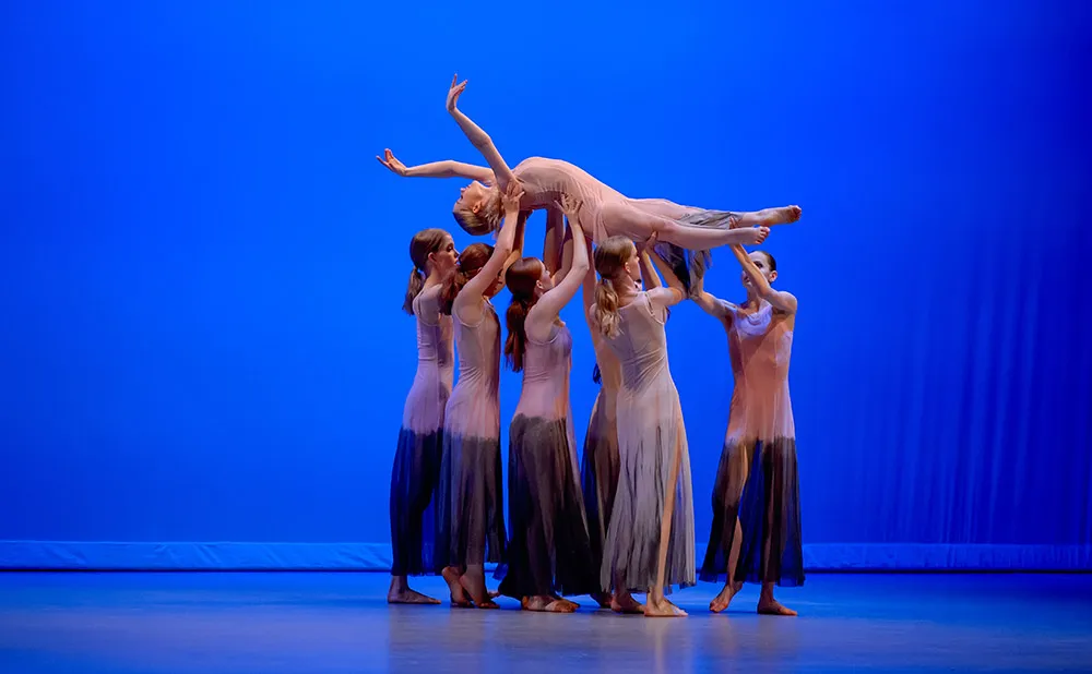 Contemporary dance performance with one dancer lifted above the other dancers